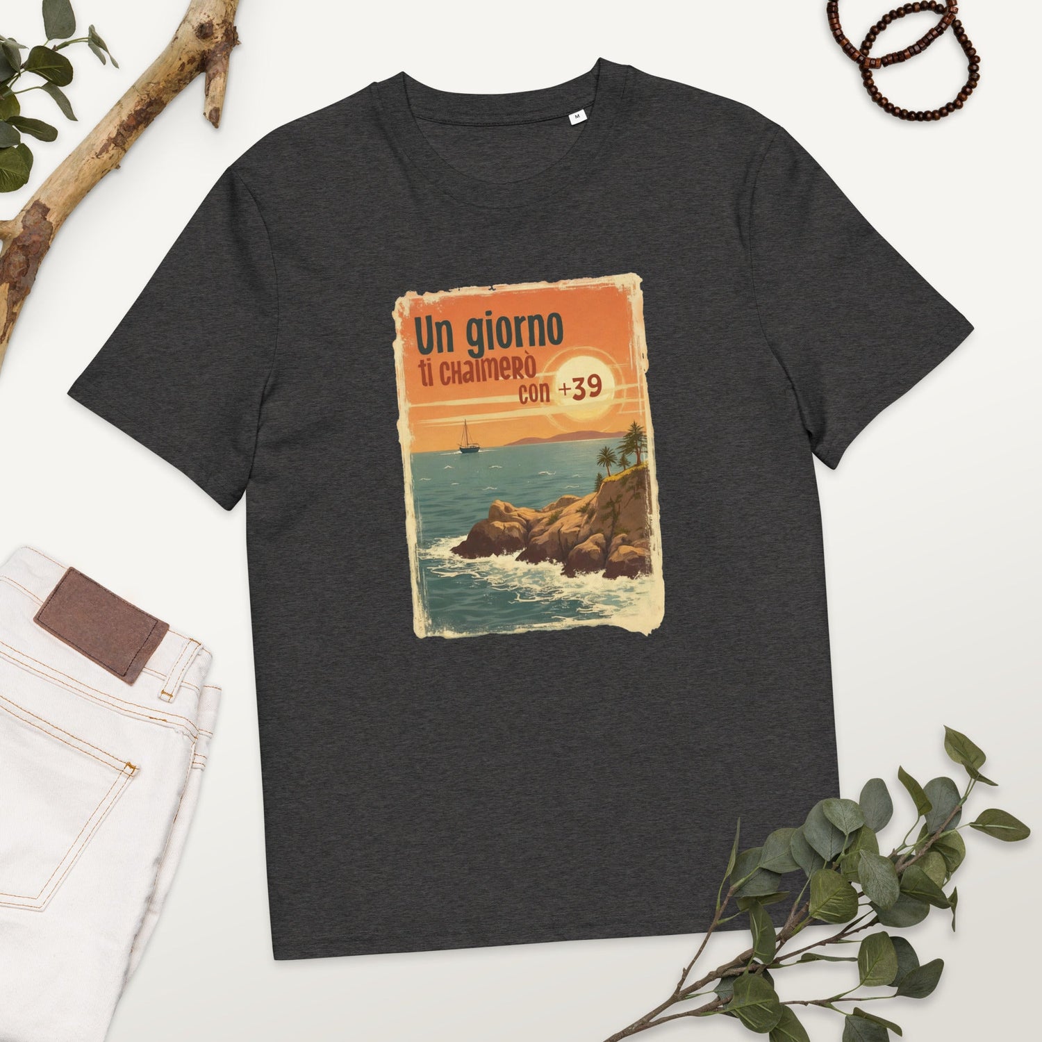 Unisex-T-Shirt aus Bio-Baumwolle mit Frontdruck „Un giorno ti chiamerò con +39“ vor einem Sonnenuntergangs-Motiv mit Küste, Segelboot und Palmen – inspiriert von italienischer Sehnsucht und Vintage-Postkartenstil.
