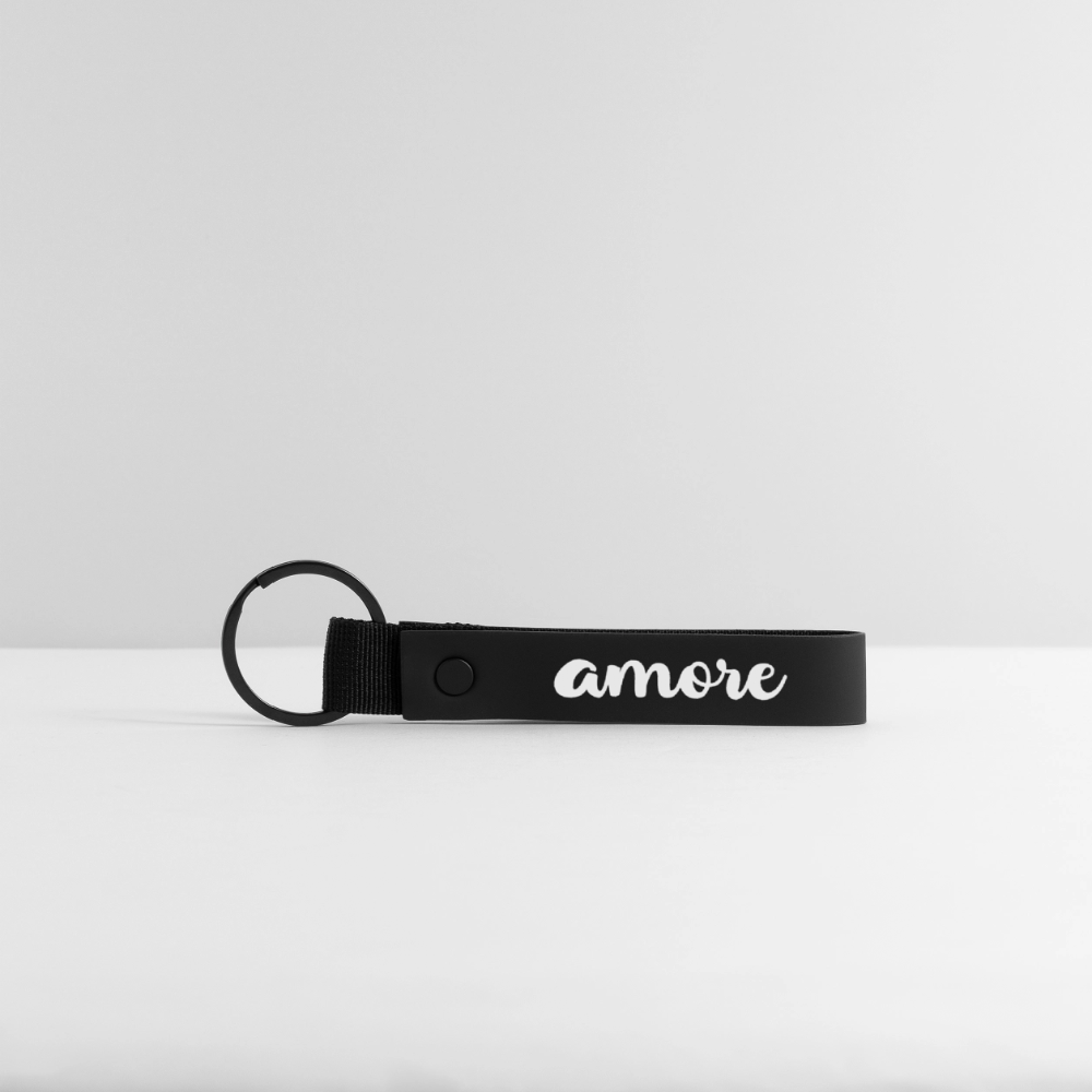 Schwarzer Schlüsselanhänger mit weißem „Amore“-Schriftzug in Kursivschrift, großer Schlaufe und matter Oberfläche – minimalistisch auf weißem Hintergrund