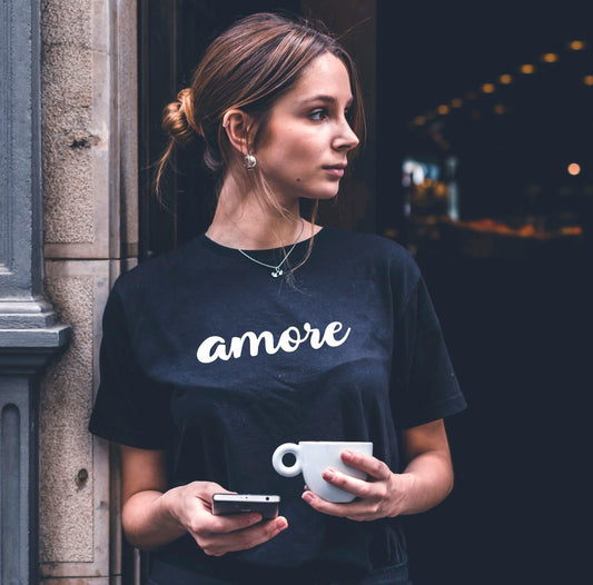 Frau trägt schwarzes Bio-Baumwoll-T-Shirt mit „Amore“-Schriftzug – minimalistisches Design, nachhaltig produziert, Teil der Kollektion „Amore d’Oro“ von Passione Italiana.