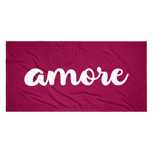 Bordeauxfarbenes Handtuch mit weißem „Amore“-Schriftzug am Strand – Liebesbotschaft trifft italienisches Design.