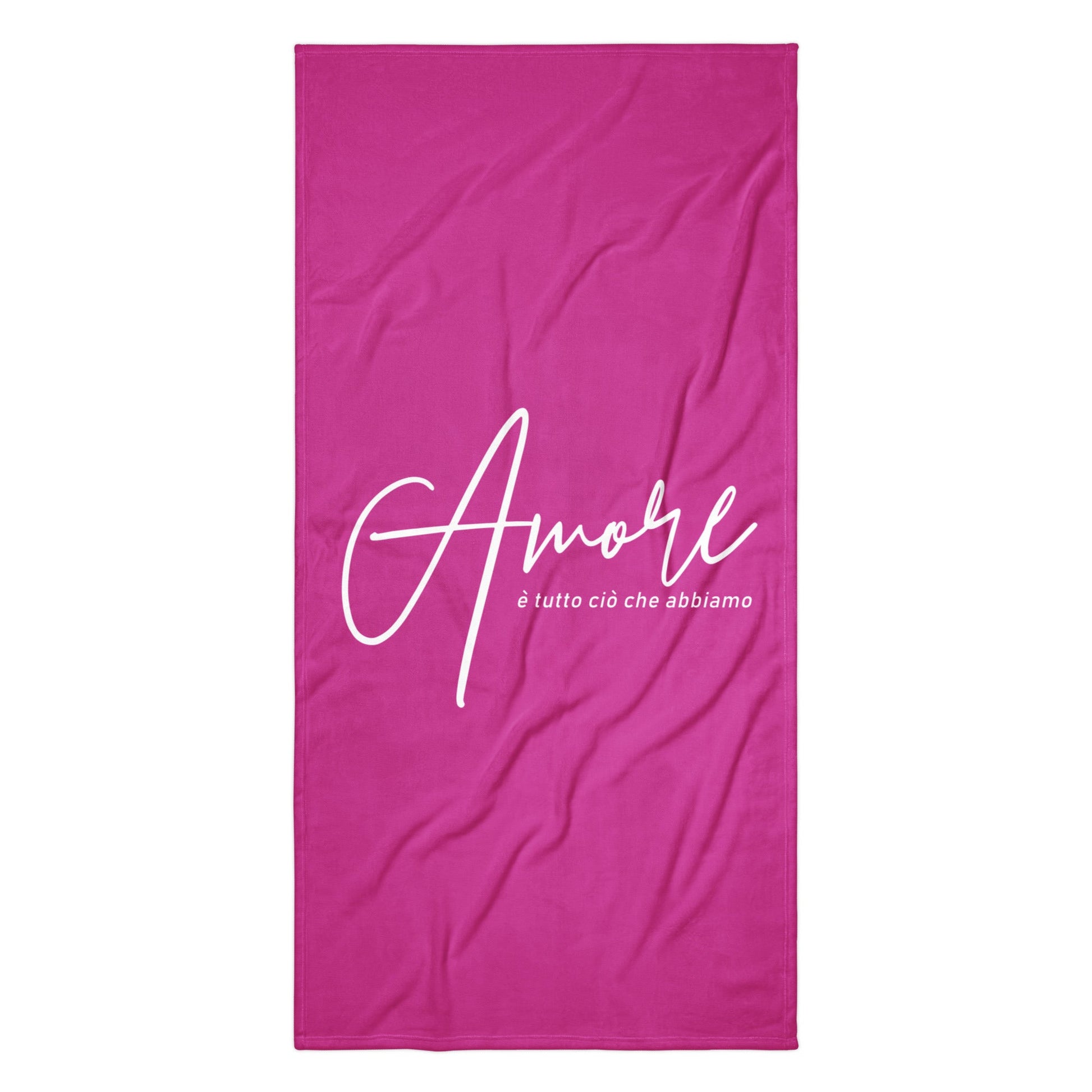 Handtuch mit weißem Schriftzug „Amore è tutto ciò che abbiamo“ am Strand – Liebesbotschaft trifft italienisches Design.