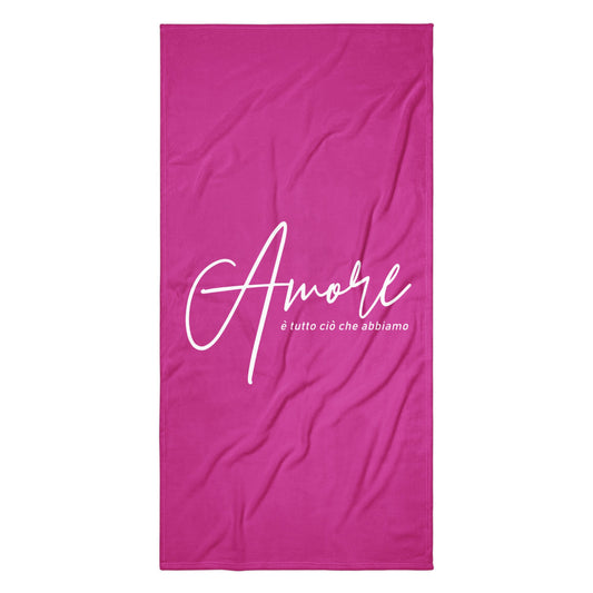 Handtuch mit weißem Schriftzug „Amore è tutto ciò che abbiamo“ am Strand – Liebesbotschaft trifft italienisches Design.