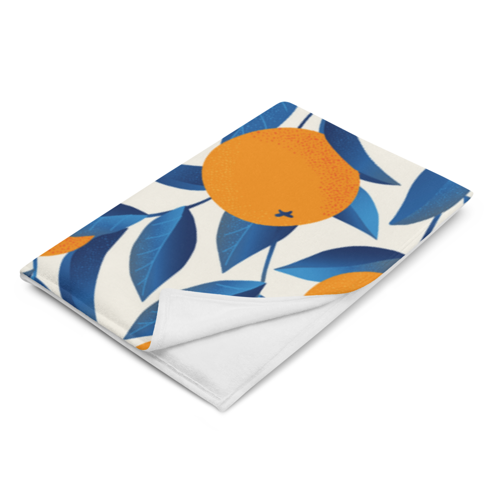 Detailansicht einer Decke mit Orangenprint und dunklen Blättern, gefaltet am Rand

